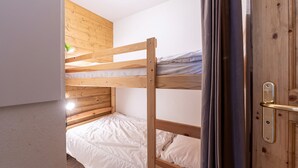 A bunk bed room with wooden walls and a door. - Apartment 'Ty Aravis' with Mountain View and Balcony (La Giettaz)