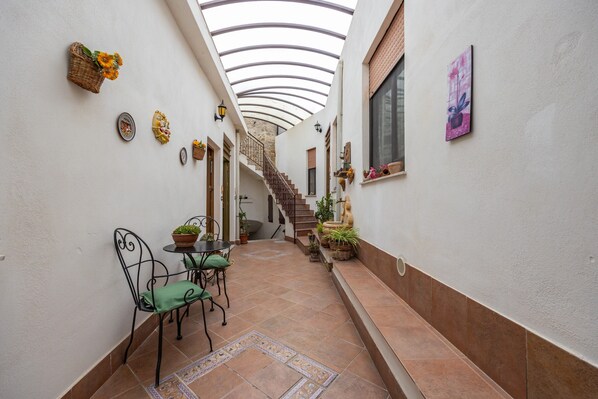 A narrow corridor with a tiled floor, a staircase, and a small table with chairs.