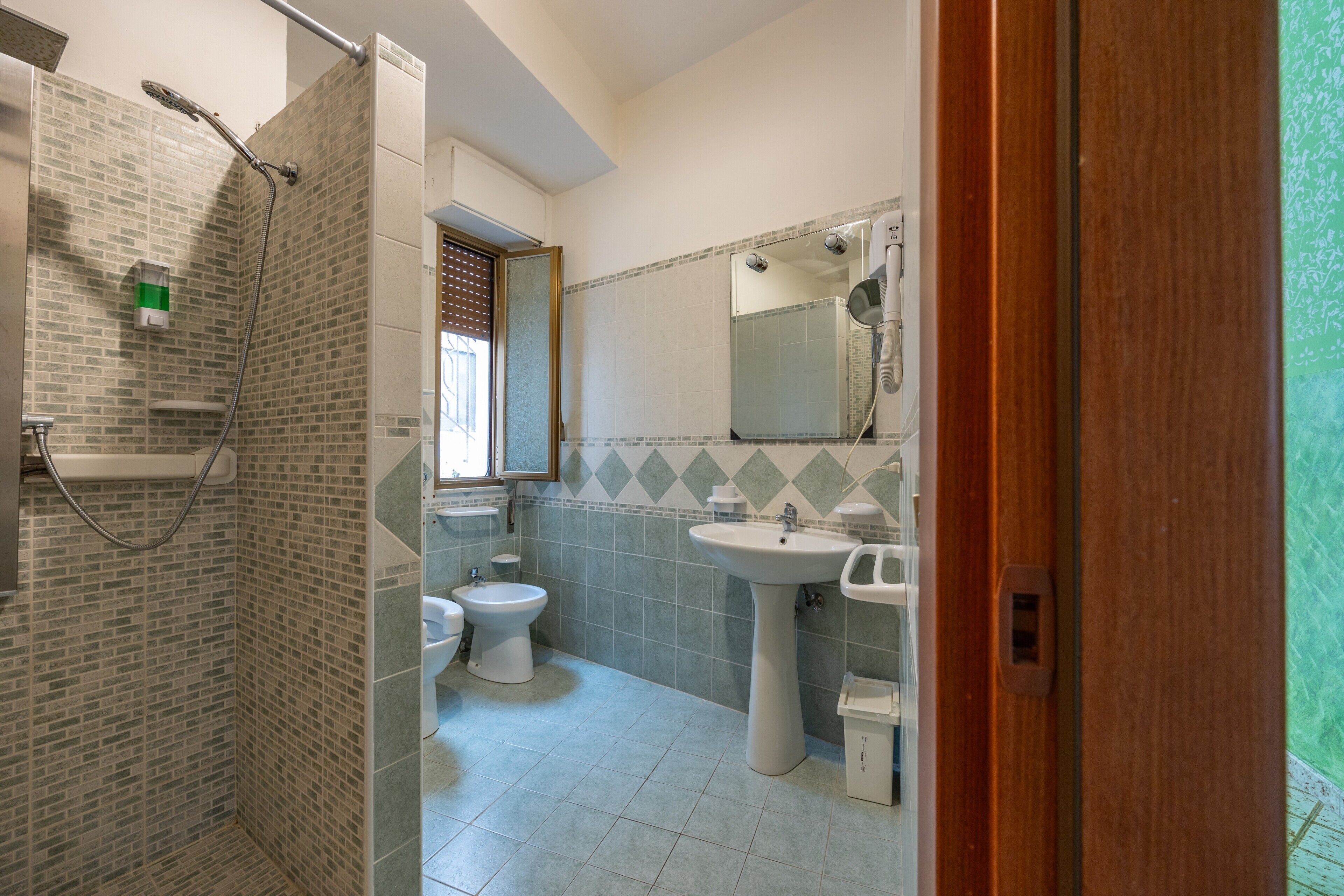 A bathroom with a shower, toilet, bidet, and sink.