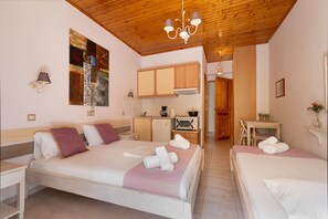 A hotel room with two beds, a kitchenette, a dining area, and a wooden ceiling.