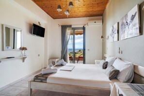 Ein Schlafzimmer mit Bett, Fernseher, Balkon mit Tisch und Stühlen sowie Bildern an der Wand.