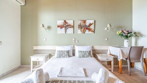 Una habitación de hotel con cama, mesitas de noche, una silla y obras de arte en la pared.