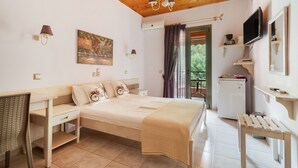 Ein Schlafzimmer mit einem Bett, Nachttischen, einem Schreibtisch, einem Sessel, einem Fernseher und einem Fenster mit Vorhängen.