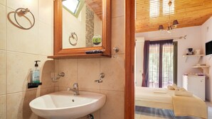 Ein Badezimmer mit Waschbecken, Spiegel, Handtuchhalter und Pflegeprodukten.