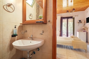 A bathroom with a sink, mirror, towel ring, and toiletries. - Studio Apartment 'Nontas Homes 34' with Mountain View, Wi-Fi and Air Conditioning (Kalamitsi)