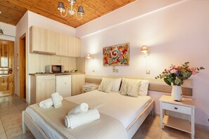 Un dormitorio con cama, mesita de noche, lámpara, obra de arte y una zona de cocina.
