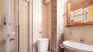 A bathroom with a shower, toilet, sink, and a mirror.