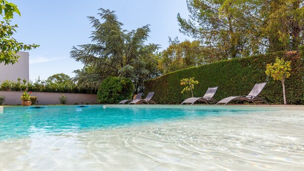 A swimming pool with clear water, surrounded by a hedge and trees. - Apartment 'Havre De Paix' with Shared Pool, Private Terrace and Wi-Fi (Marseille)