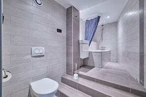 A modern bathroom with a toilet, shower, and sink.