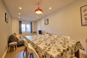 A dining area with a table, chairs, a sofa, and a TV.