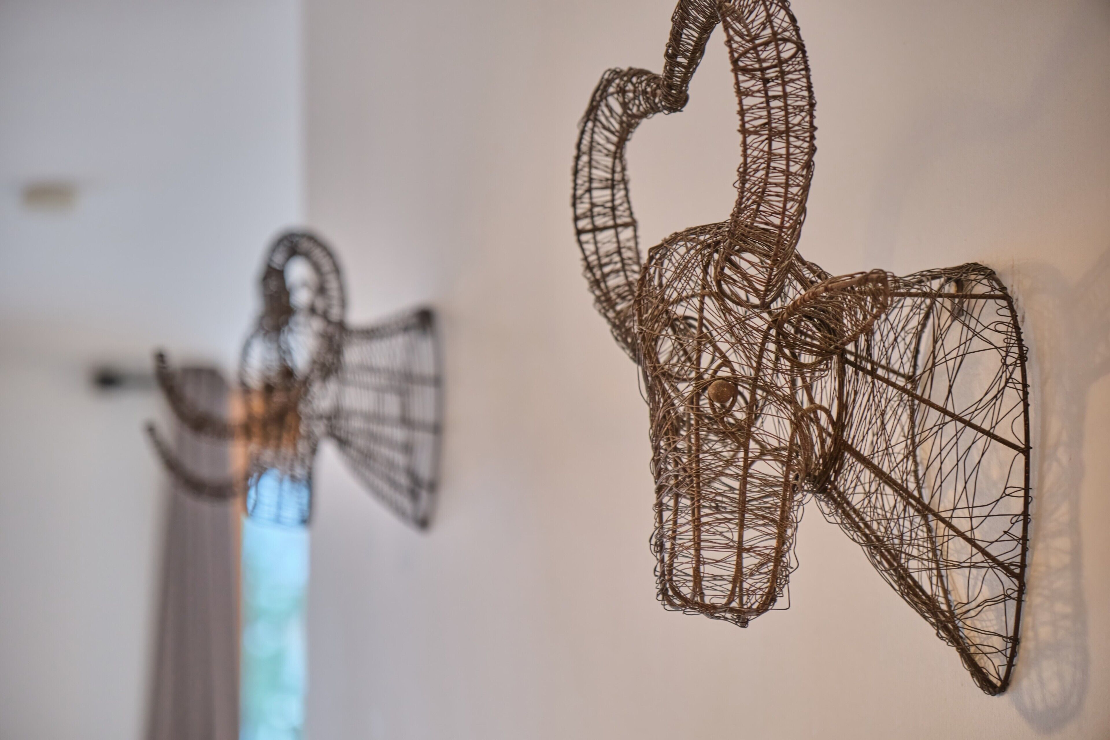 Two wire sculptures of a swan and a figure with a trumpet.
