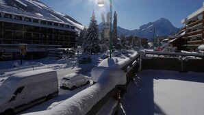 Una strada innevata con edifici, un cartello con la scritta 'EJANDRI' e una montagna sullo sfondo.