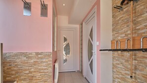 Um corredor com parede de pedra, parede rosa e uma porta com painel de vidro.