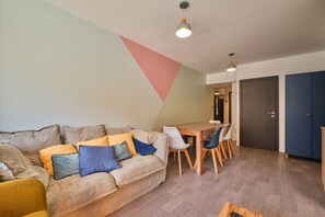 Un salon moderne avec un canapé, une table à manger, des chaises et un plancher en bois.