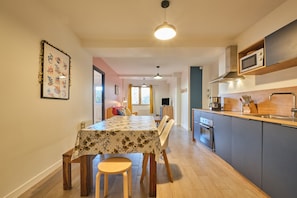 A modern kitchen with a dining area, wooden flooring, and a ceiling light. - With Mountain Views at the Apartment 'Marmotte 105' (Les Deux Alpes)