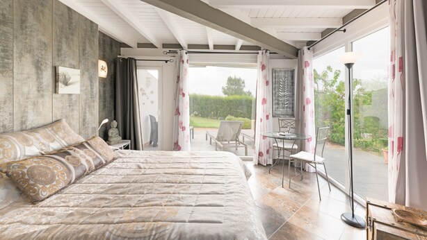 A bedroom with a large bed, a small table, and a chair, and a view of the outdoors. - Holiday Home 'Sobreirinho - Selão Da Eira' with Sea View, Shared Pool and Wi-Fi (São Teotónio)