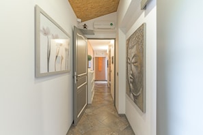 A hallway with artwork on the walls, a wooden ceiling, and an air conditioning unit.