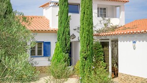A two-story house with a tiled roof, a blue door, and a white exterior. - Holiday Home 'Casa Alecrim - Selão Da Eira' with Sea View, Wi-Fi & Air Conditioning (S.Teotónio)