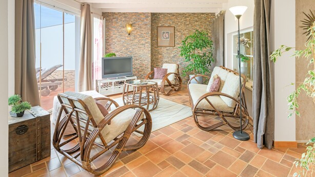 A living room with wicker furniture, a television, and a stone wall. - Holiday Home 'Casa Alecrim - Selão Da Eira' with Sea View, Wi-Fi & Air Conditioning (S.Teotónio)