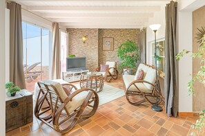 A living room with wicker furniture, a television, and a stone wall.