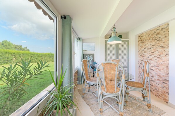 Ein Balkon mit Korbstühlen, einem Tisch und Blick auf Grünflächen.