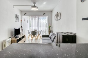 Una sala de estar moderna con televisor, sofá, mesa de comedor y sillas.