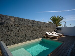 Una piscina amb gandules, una paret de pedra i un pont d'obra.