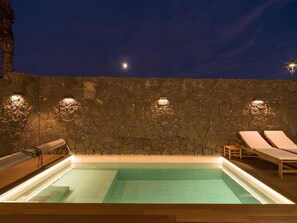 Paret de pedra amb una piscina i dues gandules.