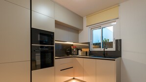 A modern kitchen with built-in appliances, a window with a view, and a tiled floor.