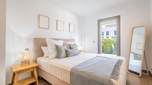 A bedroom with a bed, bedside lamp, framed pictures, a mirror, and a view of greenery outside. - Apartment 'Boquer' with Shared Pool, 2 Private Terraces and Wi-Fi (Pollença)