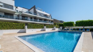 A modern building with a swimming pool, multiple balconies, and a landscaped garden. - Apartment 'Boquer' with Shared Pool, 2 Private Terraces and Wi-Fi (Pollença)
