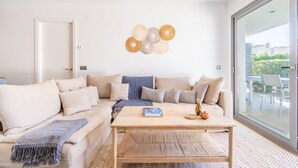 A modern living room with a sofa, coffee table, and wall decor. - Apartment 'Boquer' with Shared Pool, 2 Private Terraces and Wi-Fi (Pollença)