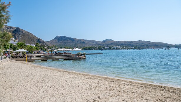 A beach with a pier, mountains in the background, and a clear sky. - Apartment 'Boquer' with Shared Pool, 2 Private Terraces and Wi-Fi (Pollença)