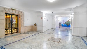 A hallway with marble flooring, a door with a metal gate, and a mural on the wall. - Awesome apartment in Fuengirola (Fuengirola)