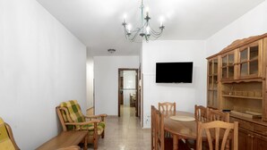 Ein Essbereich mit Holzmöbeln, einem Kronleuchter und einem Fernseher an der Wand.