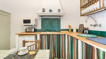 A kitchen with a microwave, a sink, a wooden countertop, and a chair.