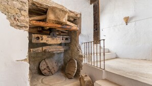 Una escalera rústica con barandilla de madera y pared de piedra.