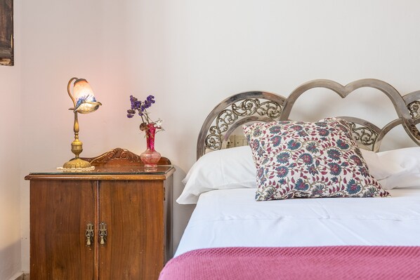 A bed with a floral pillow, a bedside lamp, and a wooden cabinet.