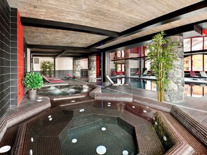 A modern indoor pool area with a hot tub, lounge chairs, and a stone pillar. - Le Télémark 5* by Interhome (Tignes)