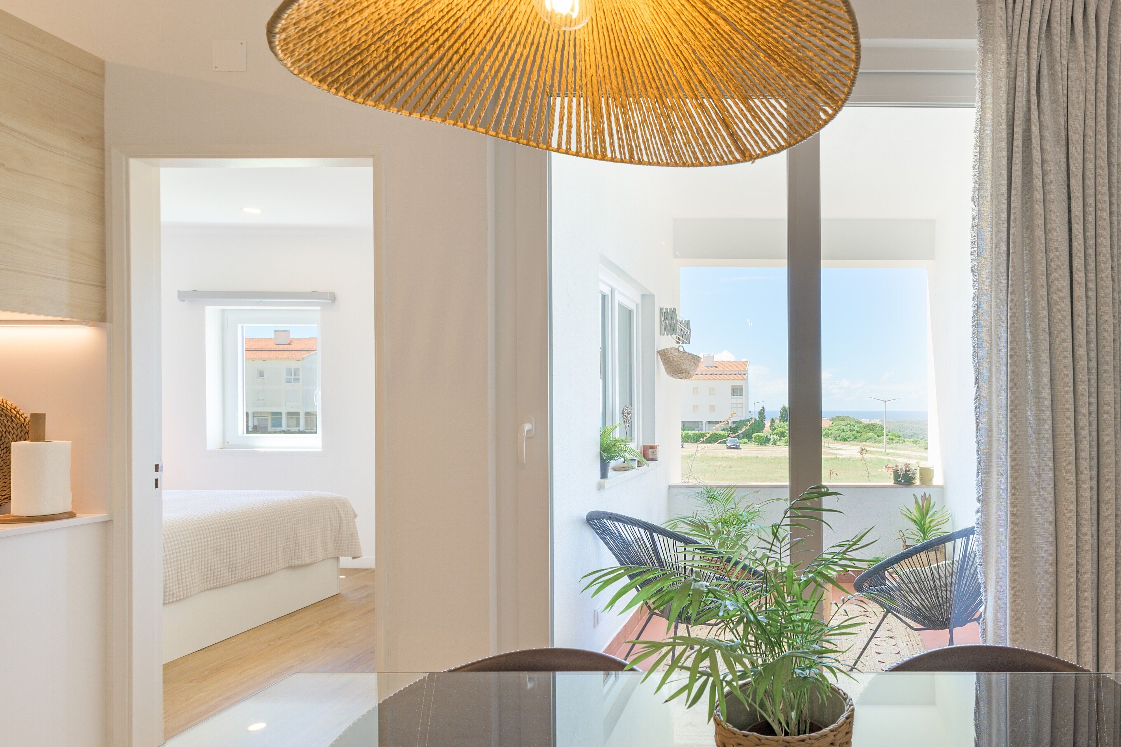 A modern room with a bed, a dining table with chairs, a large window, and a view of the outdoors.