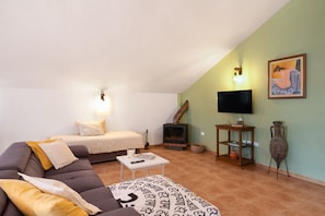 Una sala de estar acogedora con un sofá, una mesita, un televisor y una chimenea.
