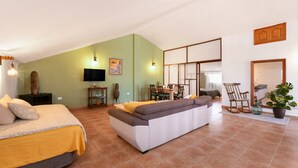 Ein geräumiger Raum mit Bett, Sofa, Esstisch, Stühlen und Fernseher.