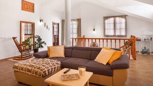 Ein geräumiges Wohnzimmer mit einer großen Couch, einem Couchtisch und einer Treppe, die in ein Obergeschoss führt.