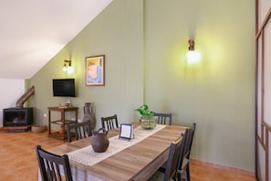 Un comedor con una mesa de madera, sillas, un jarrón, un televisor y una chimenea.