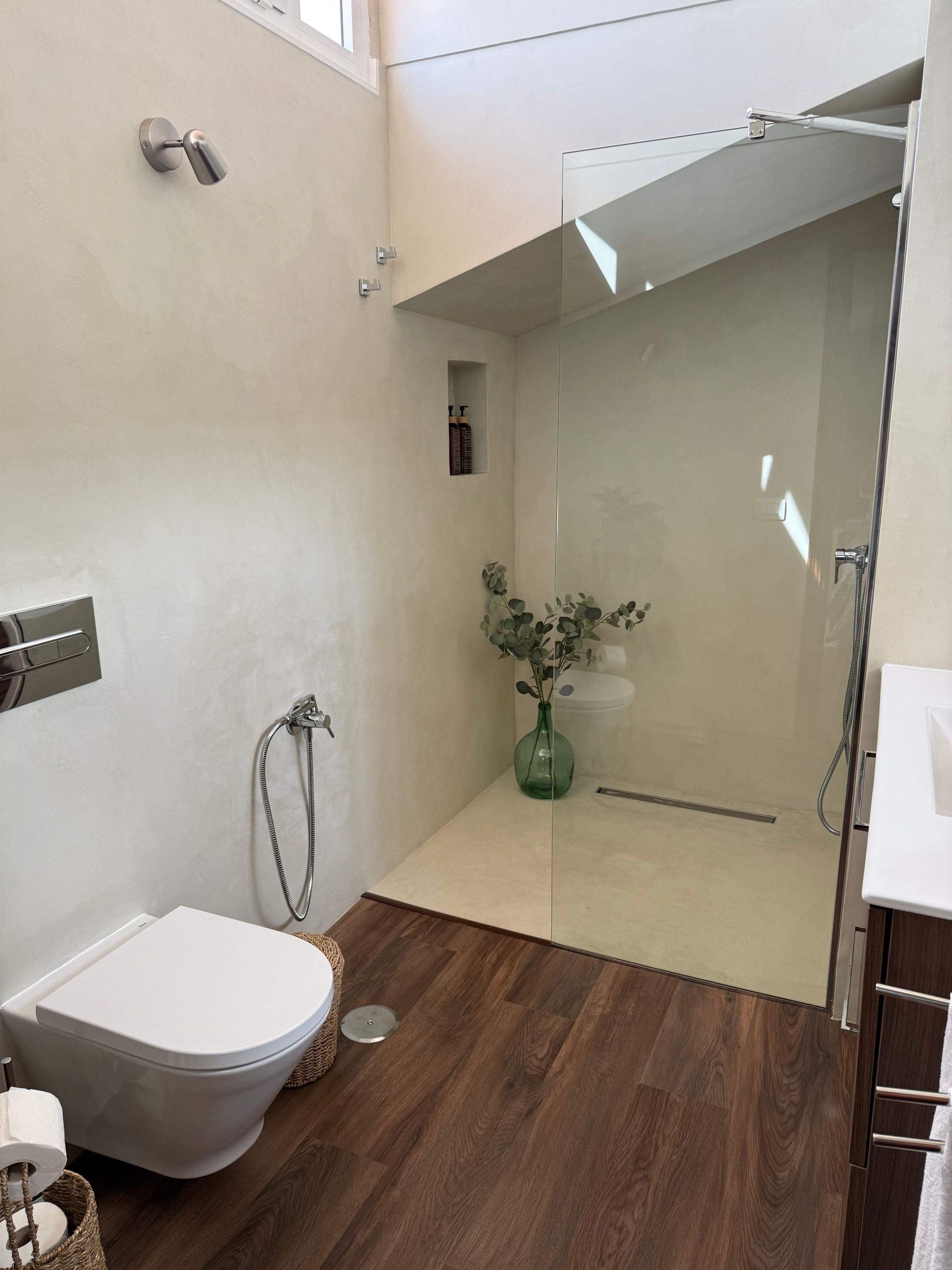 A modern bathroom with a toilet, shower, and a glass-enclosed shower area.