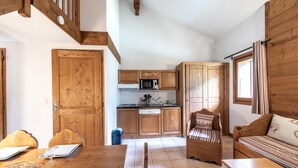 A kitchen with wooden cabinets, a microwave, and a dining area with a table and chairs.