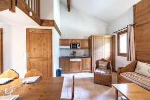 A kitchen with wooden cabinets, a microwave, and a dining area with a table and chairs.