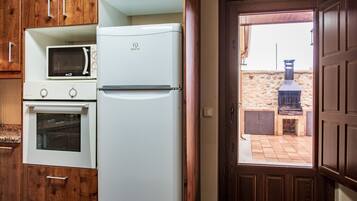 Eine Küche mit Kühlschrank, Mikrowelle, Backofen und Holzschränken.
