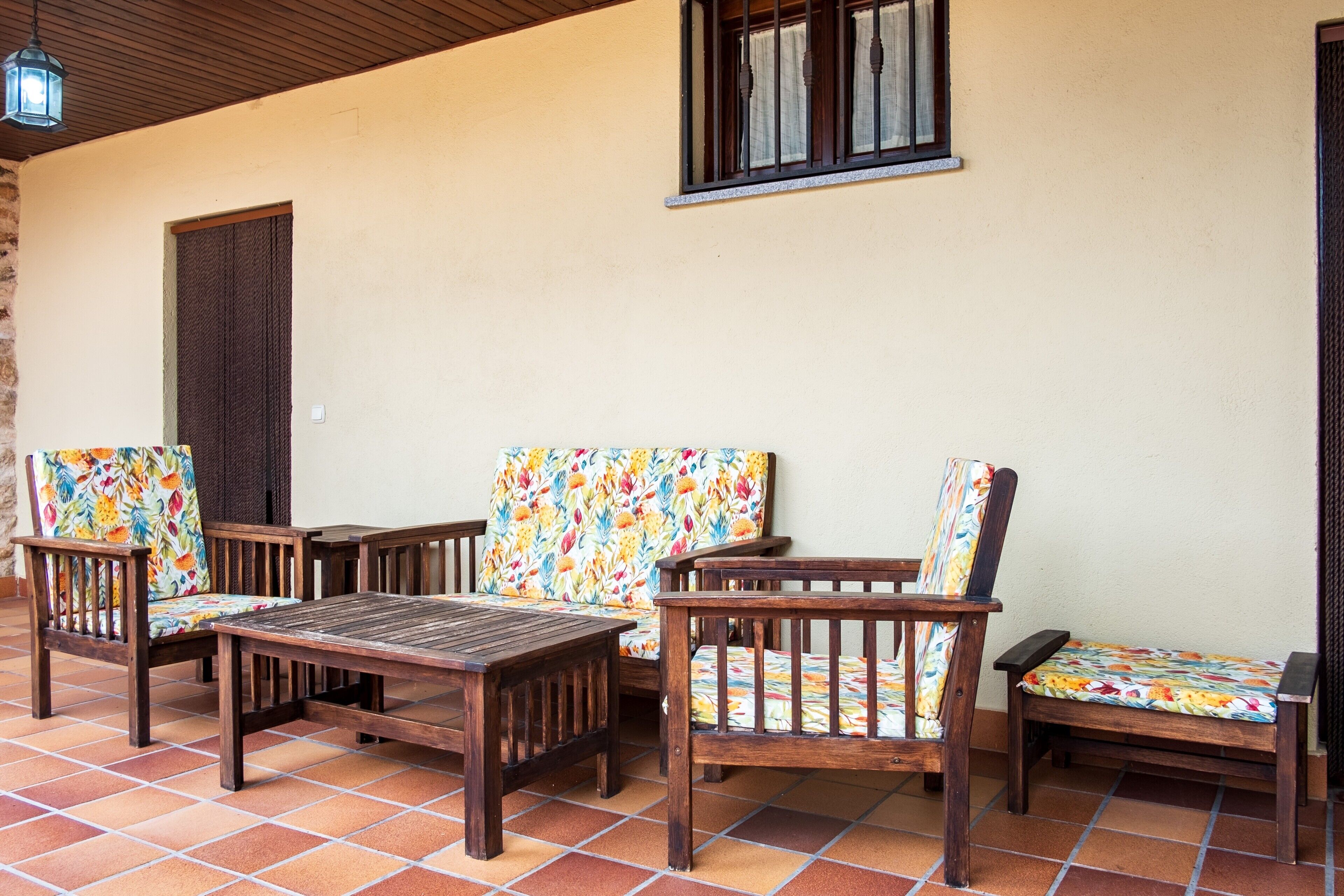 A patio with wooden furniture and a tiled floor.