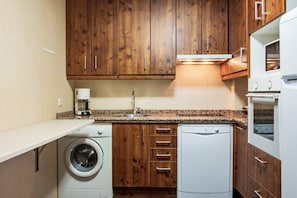 A kitchen with wooden cabinets, a washing machine, a dishwasher, and a stove.